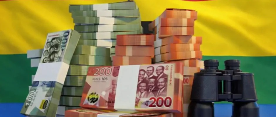 Stacks of Ghanaian cedi banknotes with the Ghana flag in the background and binoculars representing scrutiny of Ghana’s economy and rising costs in Accra