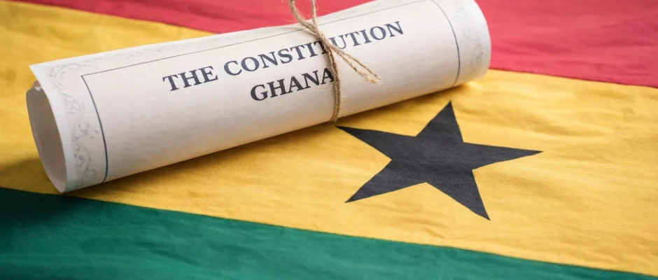 Rolled scroll titled The Constitution of Ghana resting on the Ghana flag