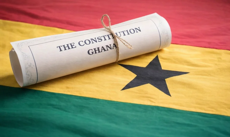 Rolled scroll titled The Constitution of Ghana resting on the Ghana flag