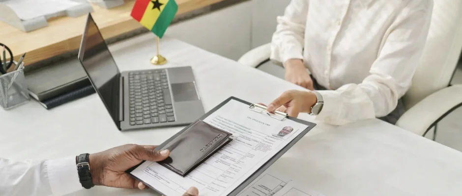 Ghana visa application process with Ghana flag on desk and passport documents