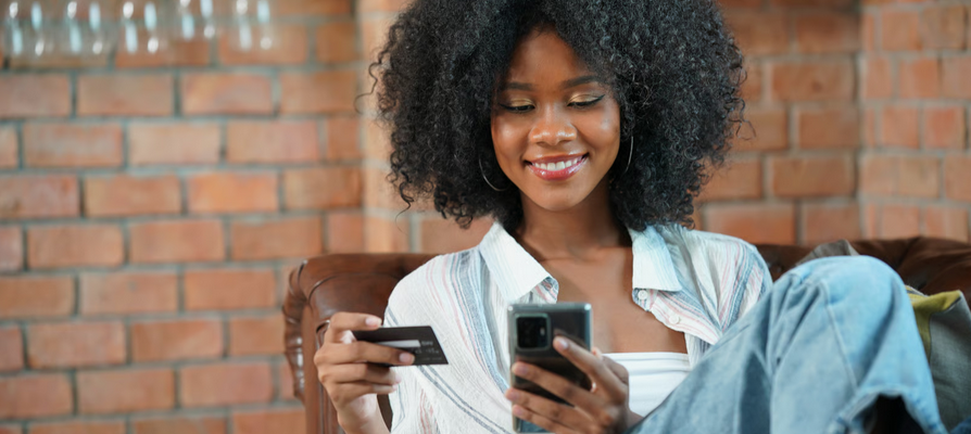 Woman using smartphone and bank card for digital payments representing Ghana financial inclusion policy, mobile banking, and fintech access.