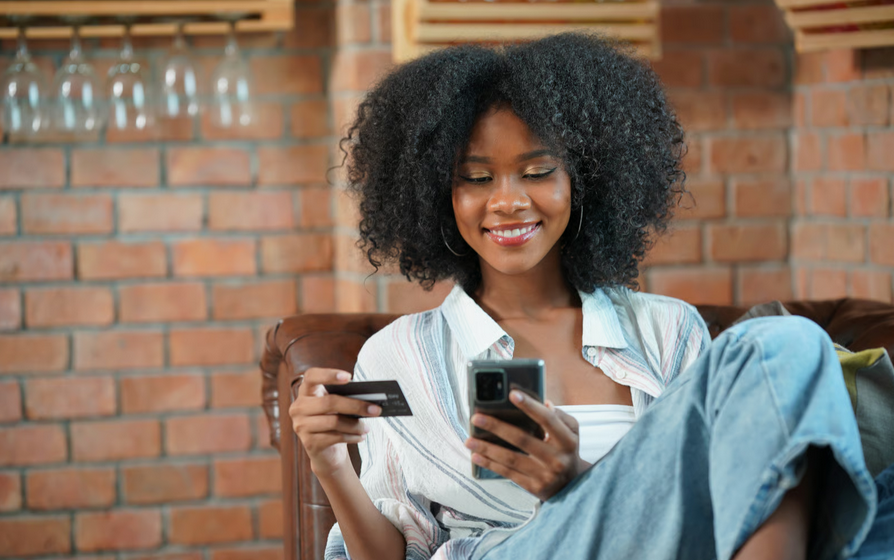 Woman using smartphone and bank card for digital payments representing Ghana financial inclusion policy, mobile banking, and fintech access.