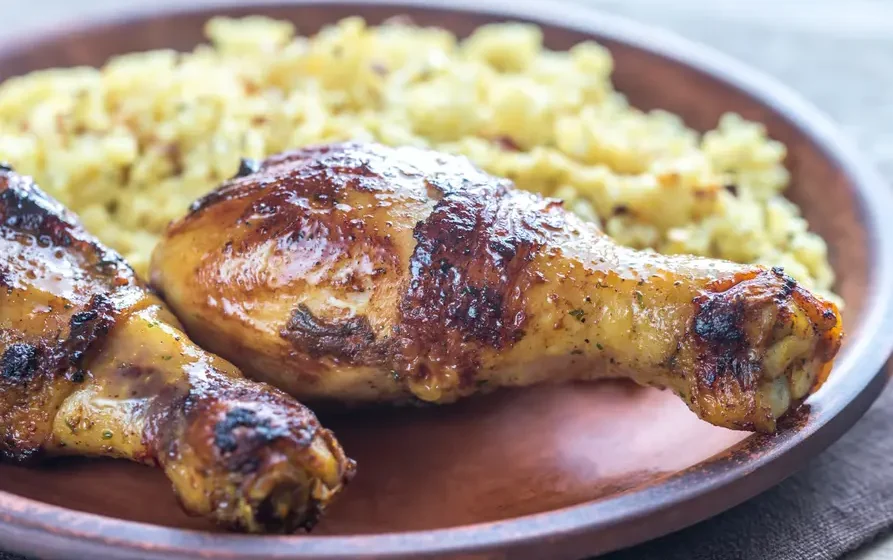 Traditional Ghanaian jollof rice served with baked chicken on a plate