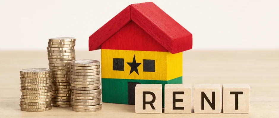 Toy wooden house painted in Ghana flag colors beside coins and scrabble tiles spelling rent, representing the Ghana rent control crackdown
