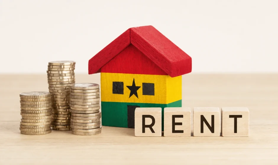Toy wooden house painted in Ghana flag colors beside coins and scrabble tiles spelling rent, representing the Ghana rent control crackdown