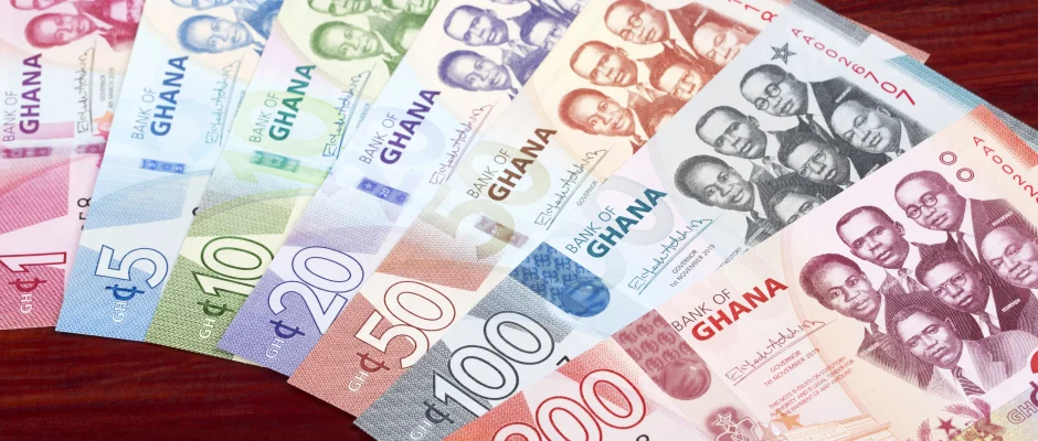 Ghanaian cedi banknotes spread across a wooden table