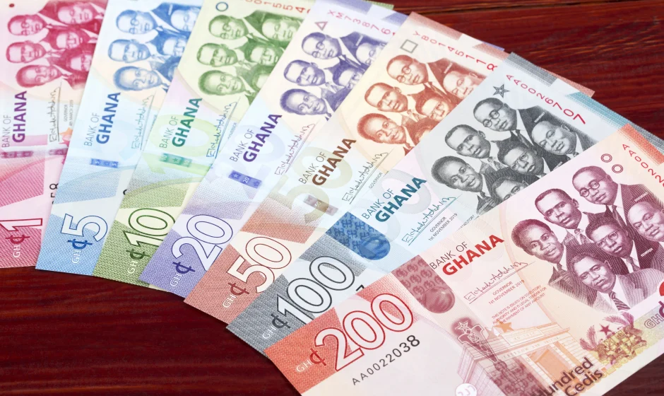 Ghanaian cedi banknotes spread across a wooden table