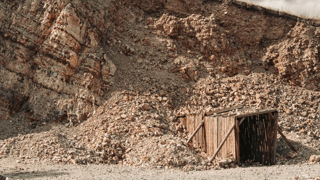 Weathered wooden entrance amidst rocky terrain of an old mine.