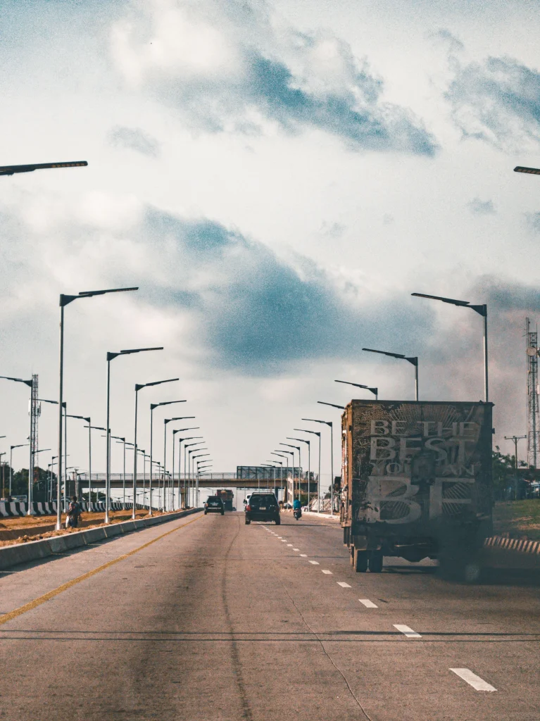 View of highway traffic under a cloudy sky in Abuja, showcasing street lamps lining the road.